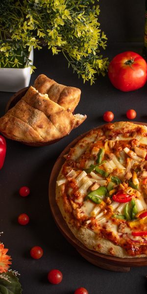 pizza with cheese and tomatoes on brown wooden round plate